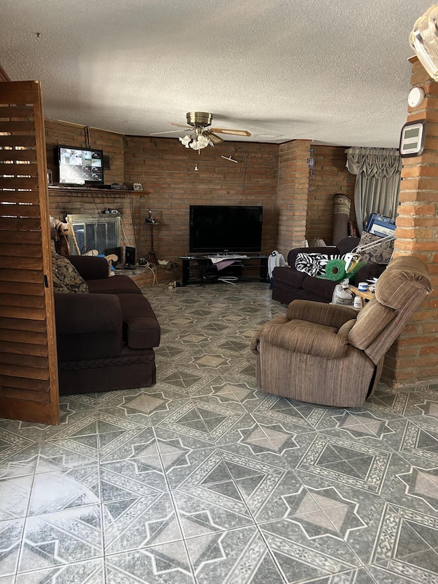 tiled living room with a textured ceiling, brick wall, ceiling fan, and a fireplace