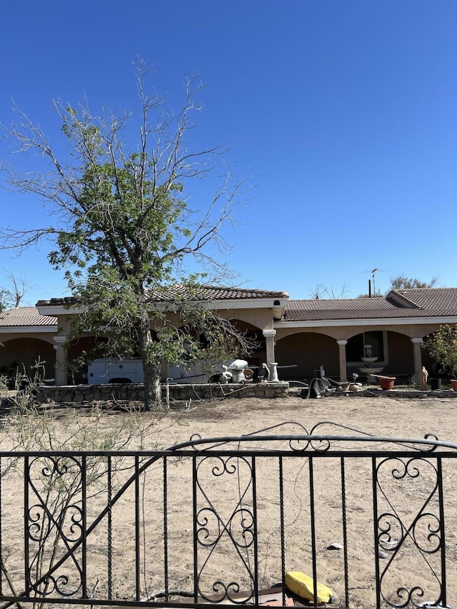 view of front facade with stucco siding, a tile roof, and fence