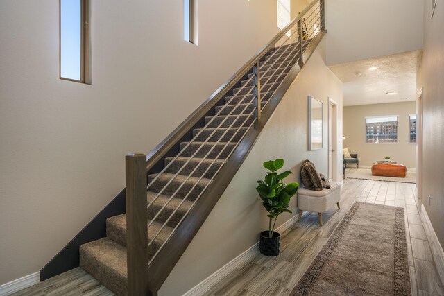 stairway with hardwood / wood-style floors and a textured ceiling