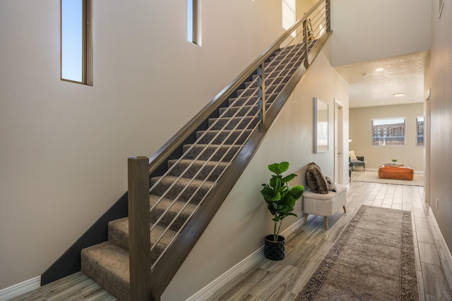 stairway featuring a high ceiling and hardwood / wood-style flooring