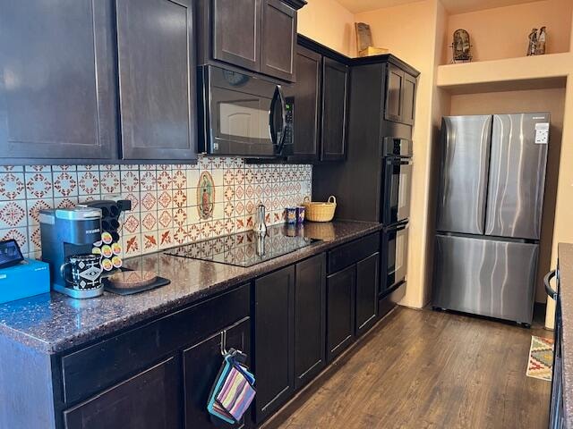 kitchen with dark stone counters, dark hardwood / wood-style flooring, backsplash, and black appliances