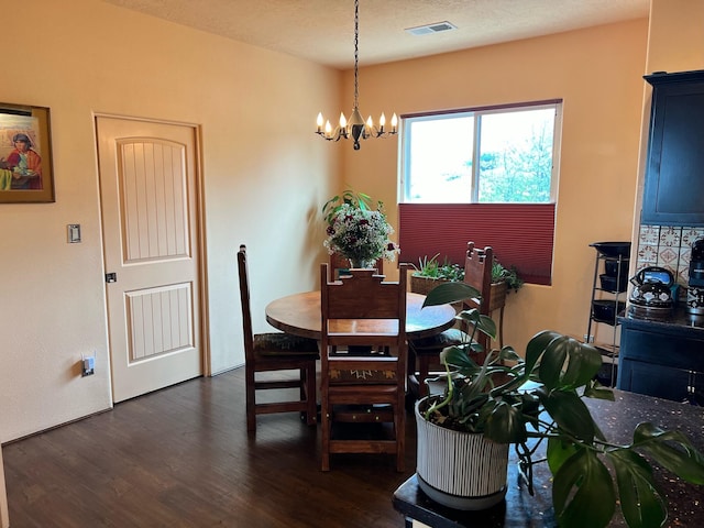 dining space with dark hardwood / wood-style flooring, a textured ceiling, and a chandelier