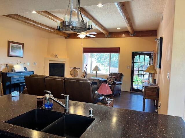 kitchen featuring ceiling fan, beam ceiling, wood-type flooring, sink, and a textured ceiling