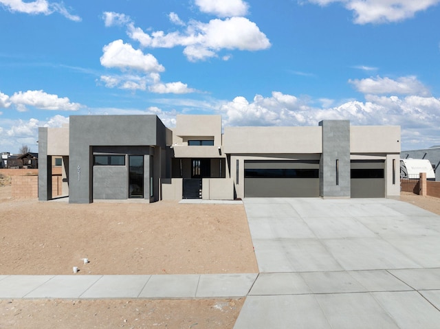 view of front of house with driveway, an attached garage, fence, and stucco siding