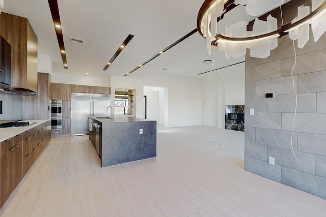 kitchen with tile walls, sink, an island with sink, and appliances with stainless steel finishes