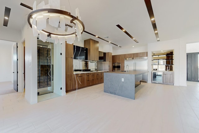 kitchen featuring wine cooler, stainless steel oven, sink, and an island with sink