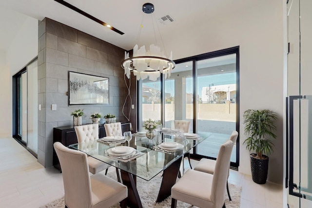 dining area featuring tile walls and an inviting chandelier