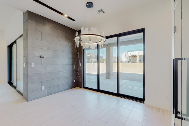 empty room with tile walls and an inviting chandelier