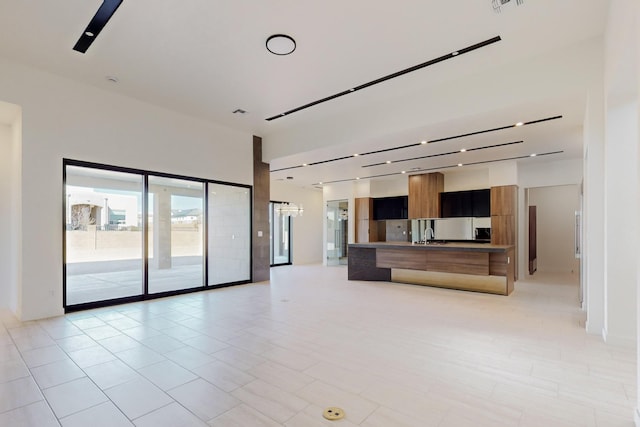 unfurnished living room featuring track lighting and sink