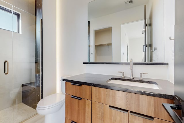 bathroom featuring vanity, toilet, and a shower with door