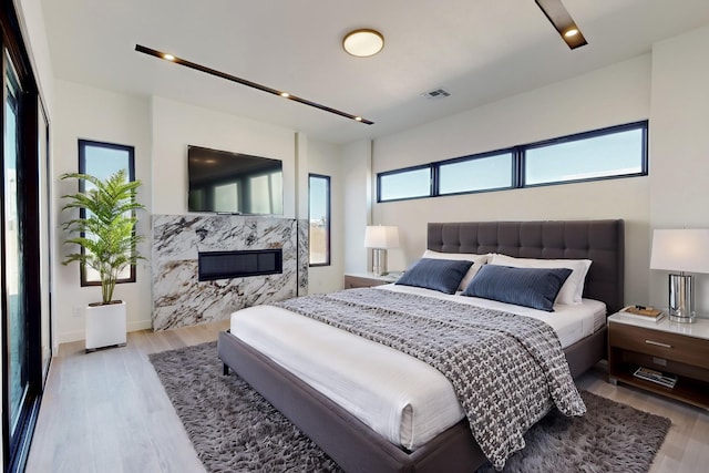 bedroom featuring a fireplace and light wood-type flooring