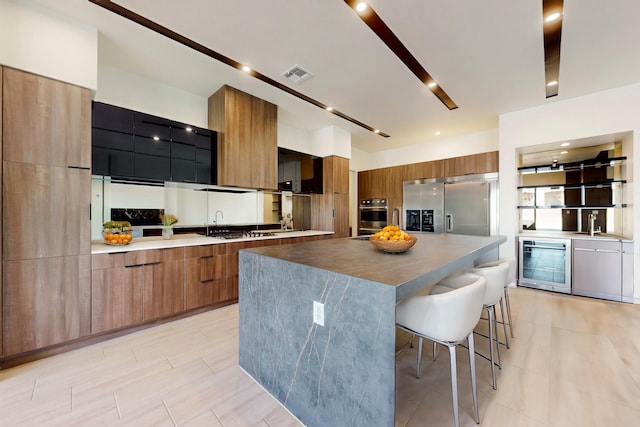 kitchen featuring wine cooler, appliances with stainless steel finishes, a large island, and a kitchen bar