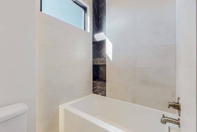 bathroom with toilet and tiled shower / bath combo