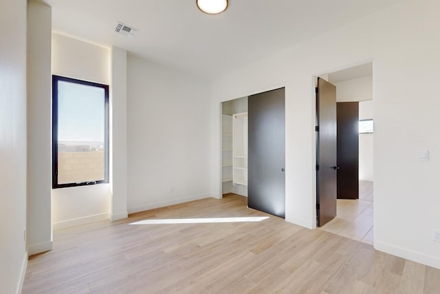 unfurnished bedroom with multiple windows, a closet, and light hardwood / wood-style flooring