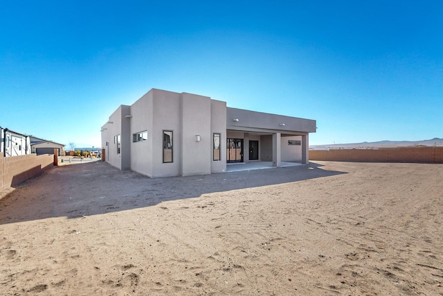 rear view of property with a mountain view and a patio area