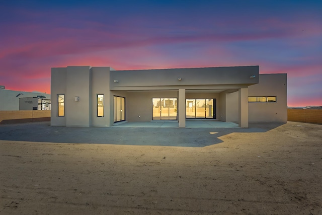 back house at dusk featuring a patio area