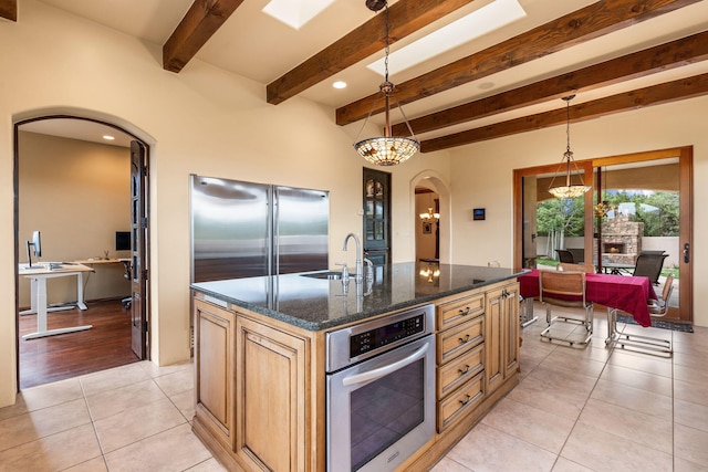 kitchen featuring pendant lighting, light tile patterned floors, stainless steel appliances, and an island with sink