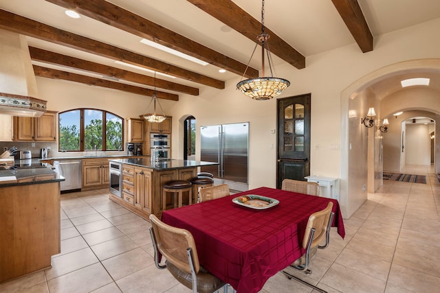 dining area featuring light tile patterned flooring, beam ceiling, and sink