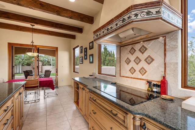 kitchen with custom range hood, black electric cooktop, hanging light fixtures, and a healthy amount of sunlight