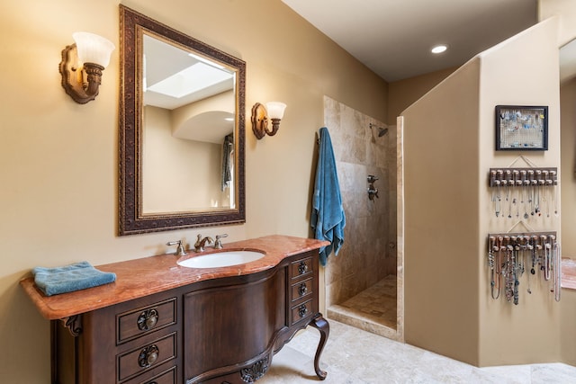 bathroom with a tile shower and vanity