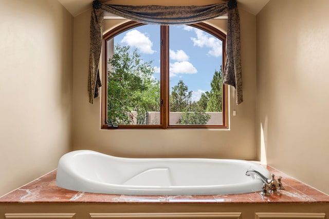 bathroom with a bathing tub and vaulted ceiling