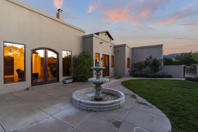 patio terrace at dusk with french doors and a lawn