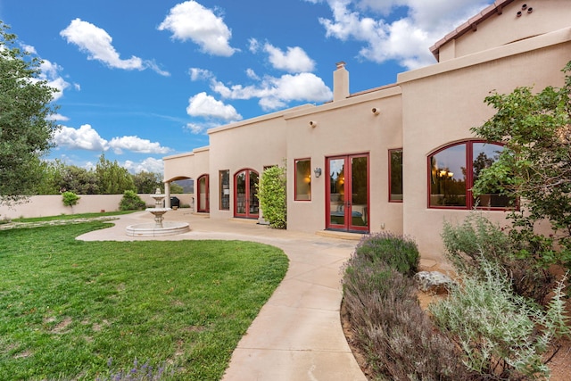 rear view of property with a lawn and french doors