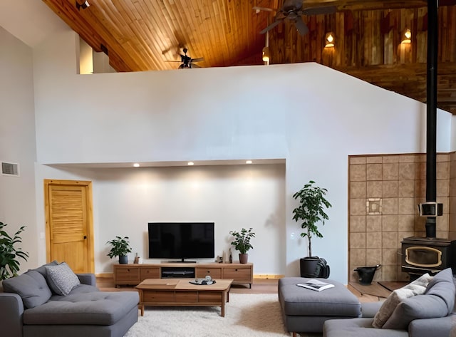 living room with a wood stove, ceiling fan, and high vaulted ceiling