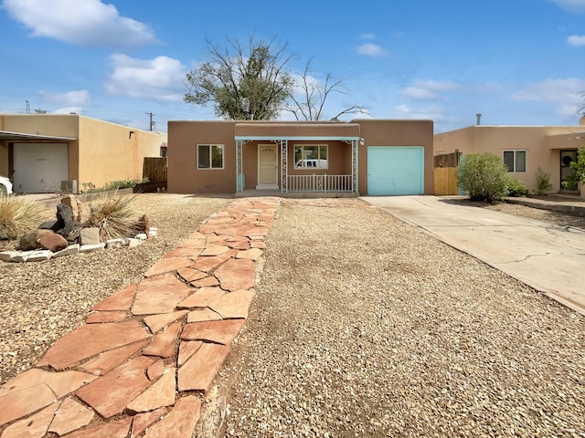 pueblo-style home with a porch and a garage