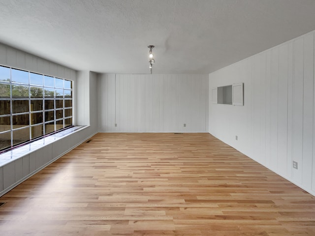 unfurnished room featuring light hardwood / wood-style flooring and wooden walls