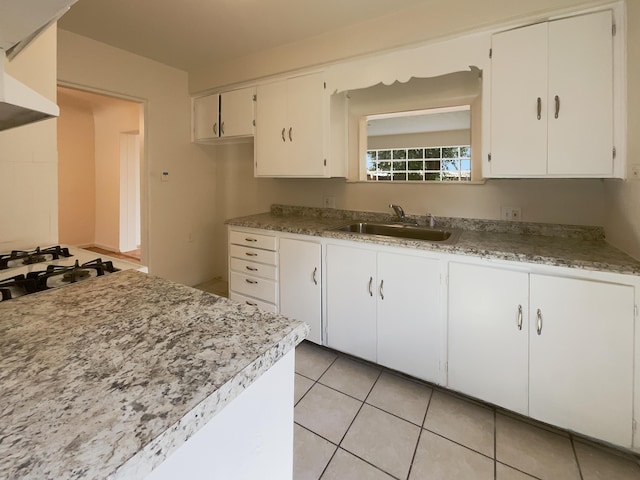 kitchen featuring white gas stovetop, sink, white cabinets, and light tile patterned floors