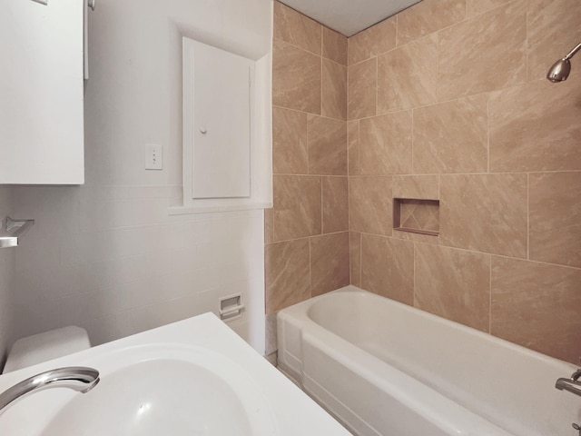 full bathroom featuring tiled shower / bath combo, toilet, and sink