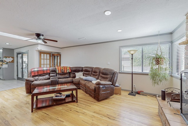 living room featuring a textured ceiling, light hardwood / wood-style flooring, ceiling fan, and crown molding