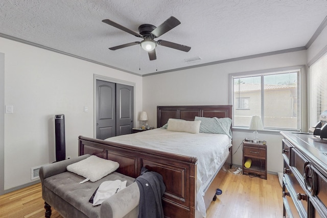 bedroom with light hardwood / wood-style flooring, ceiling fan, ornamental molding, a textured ceiling, and a closet