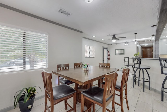 tiled dining room with ceiling fan and crown molding