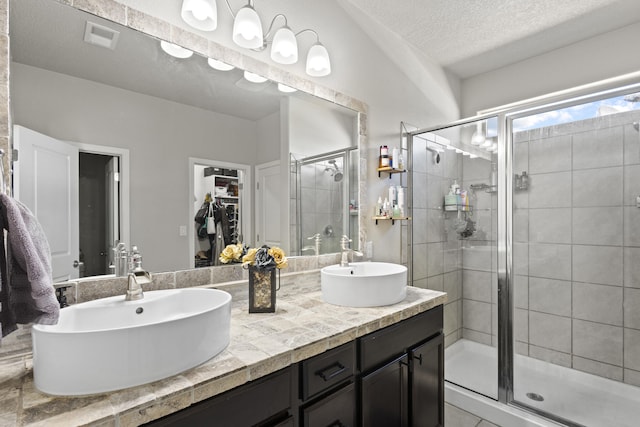 bathroom with a textured ceiling, vanity, and a shower with shower door