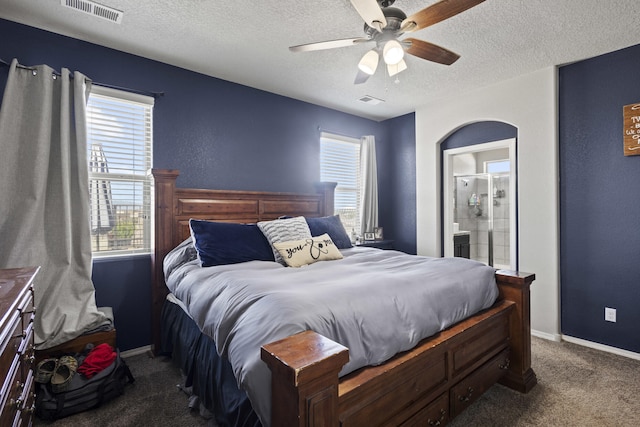 bedroom with dark colored carpet, ceiling fan, a textured ceiling, and ensuite bath