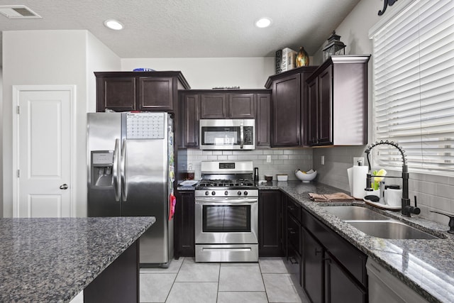 kitchen with dark stone countertops, light tile patterned floors, sink, and appliances with stainless steel finishes