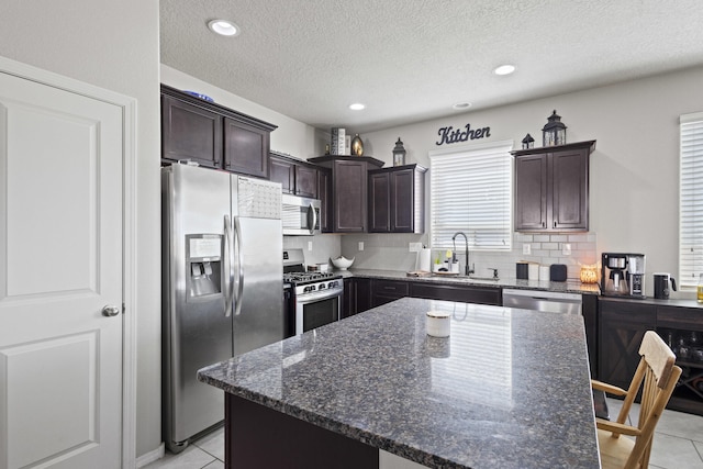 kitchen featuring a center island, sink, stainless steel appliances, and dark stone counters