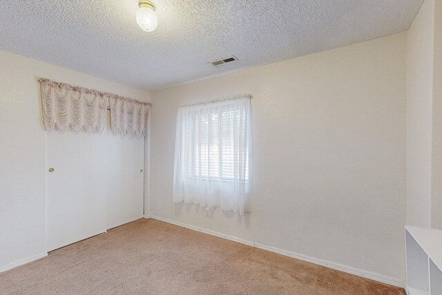 carpeted spare room with a textured ceiling