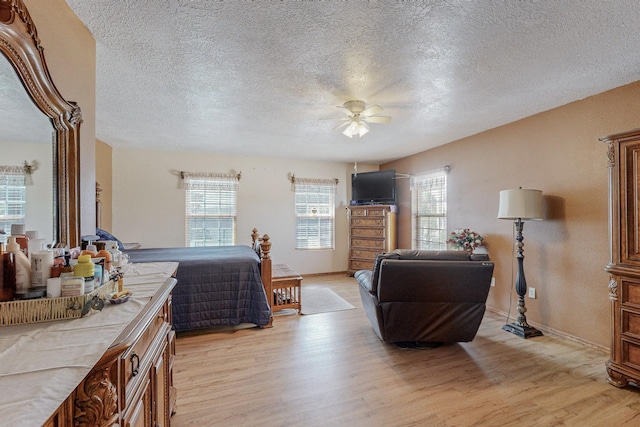 bedroom with a textured ceiling, light hardwood / wood-style floors, and ceiling fan