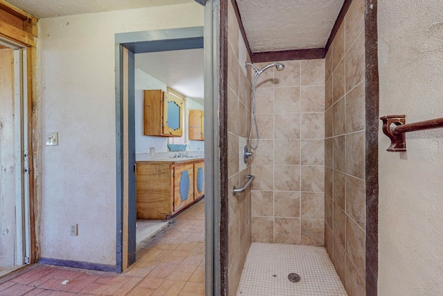 bathroom with tiled shower and vanity