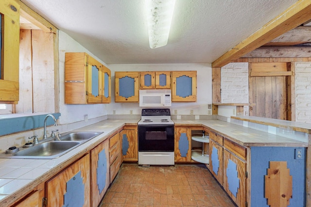 kitchen with beam ceiling, white appliances, sink, and a textured ceiling