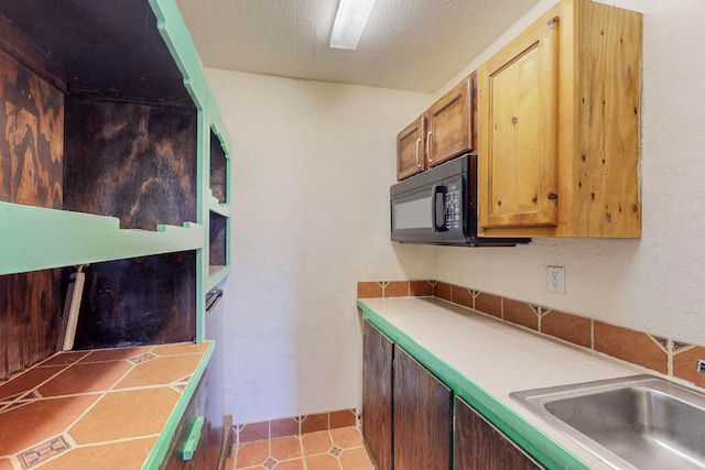 kitchen with a textured ceiling, sink, tile countertops, and light tile patterned floors