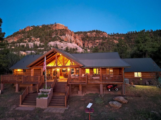 rear view of house with stairs, metal roof, log siding, and a mountain view