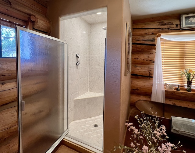 bathroom with a shower stall and log walls