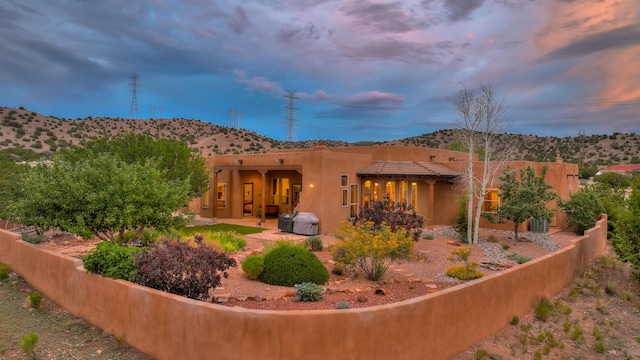 back house at dusk featuring a patio and a mountain view