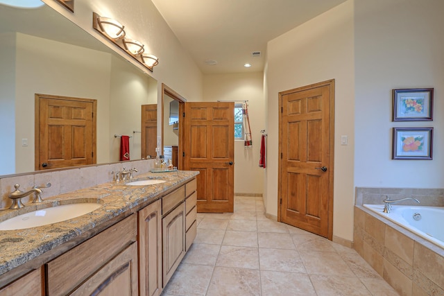 bathroom with tile patterned flooring, vanity, and a relaxing tiled tub