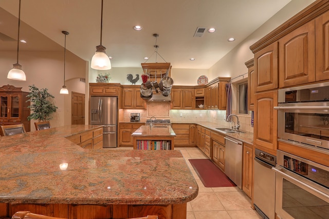 kitchen featuring sink, light stone counters, a center island with sink, appliances with stainless steel finishes, and pendant lighting