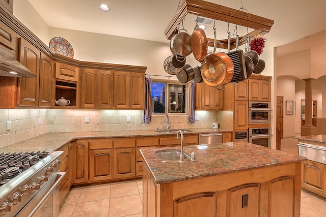 kitchen with stone countertops, sink, stainless steel appliances, and a center island with sink